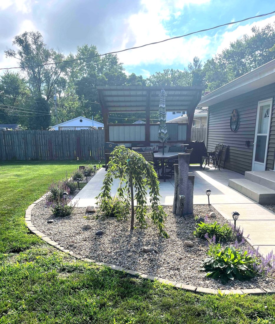 Curved garden bed beside a backyard patio